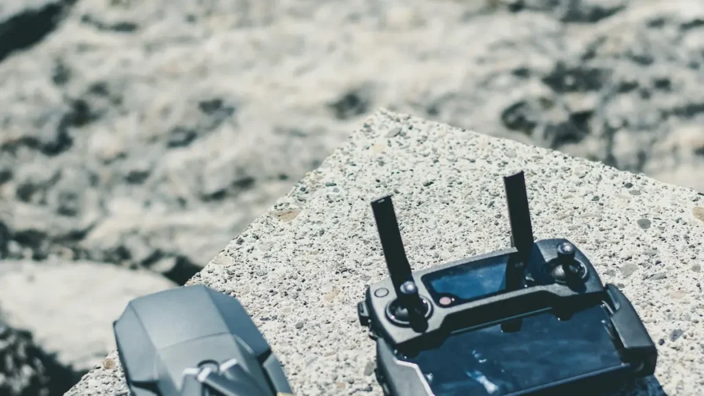 A folding drone and its controller on a concrete ledge