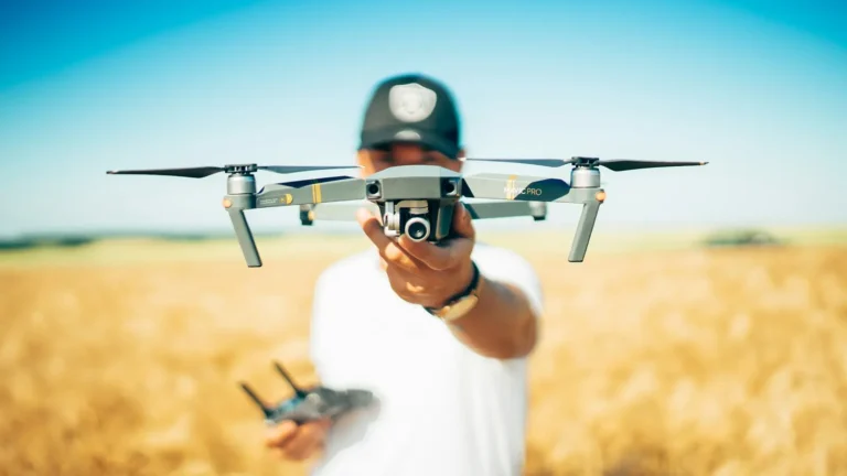 A pilot launching a small quadcopter drone in a wheat field